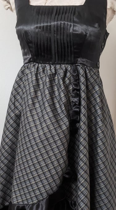 The front of a black/gold plaid and black satin flowy cocktail dress
