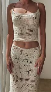 a woman in a white crochet top and white crochet skirt