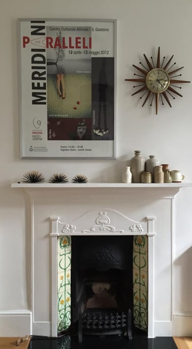 a fireplace with a clock on the mantle, assorted ceramic pieces on display