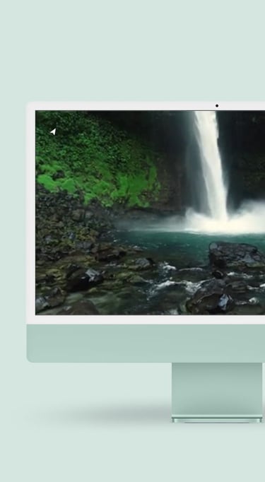 a desktop computer monitor with a waterfall in the background