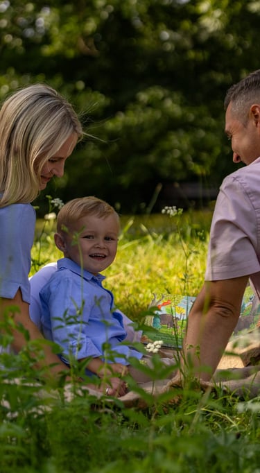 Familienshooting Coburg: Entspannte Familienzeit, Eltern mit Sohn sitzen auf einer Wiese.