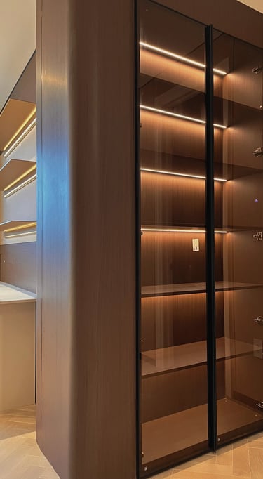 Modern dark wood display cabinet with glass doors and integrated LED shelf lighting.