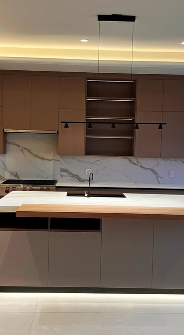 Modern luxury kitchen featuring minimalist flat-panel cabinets, marble backsplash, and large island with cove lighting.