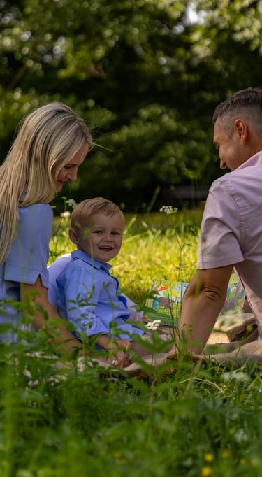 Familienshooting Coburg: Entspannte Familienzeit, Eltern mit Sohn sitzen auf einer Wiese.