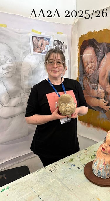 A studio photograph at the University of Chester of the artist, Christine Gallagher holding her clay head sculpture