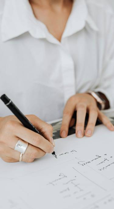 Zbliżenie na ręce kobiety podpisującej dokument długopisem, ubrana w białą koszulę