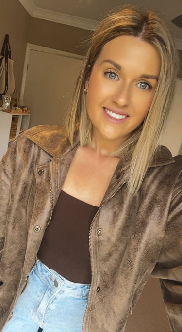 Female smiling wearing a brown jacket and jeans