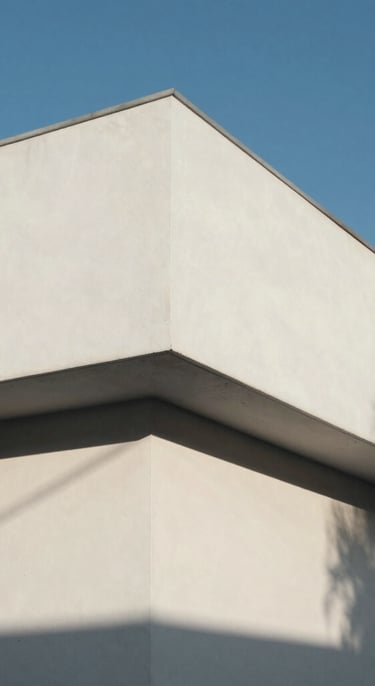 Composición geométrica minimalista de una fachada de hormigón blanco bajo luz solar directa, sombras duras y líneas puras, cielo azul despejado al fondo.