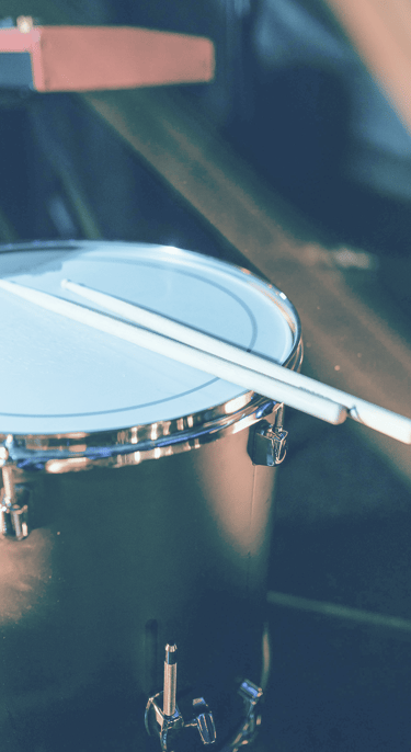 redish blue tint to upclose image of drums and drumsticks