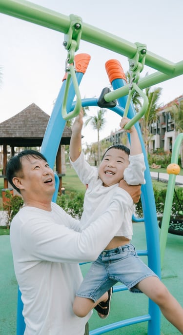 Family photography session at The Apurva Kempinski Bali playground area featuring joyful parent and child interaction.