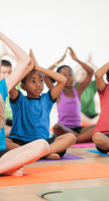 Children group yoga with rainbow colored mats