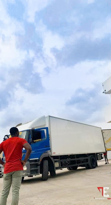 A confident man in a red t-shirt and khaki pants stands with hands on hips, overseeing operations be