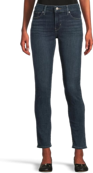 a woman in jeans and heels standing in front of a white background