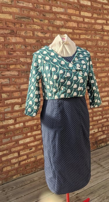 The front of a navy polka dot reversible sheath dress and green 50's inspired jacket