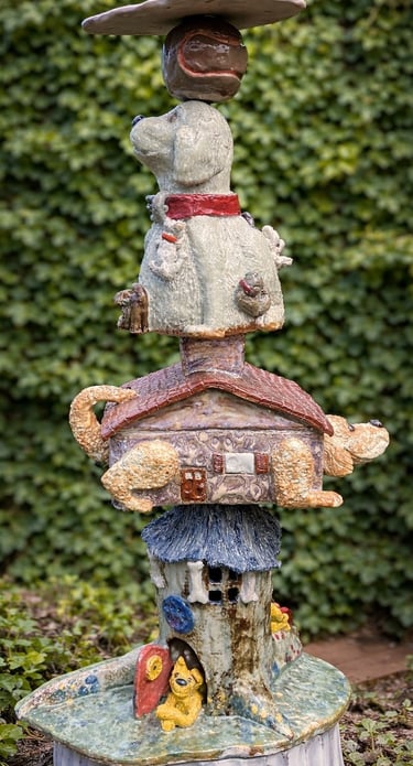 A vertical ceramic totem pole featuring a stack of various dog breeds accented with vibrant glazes.