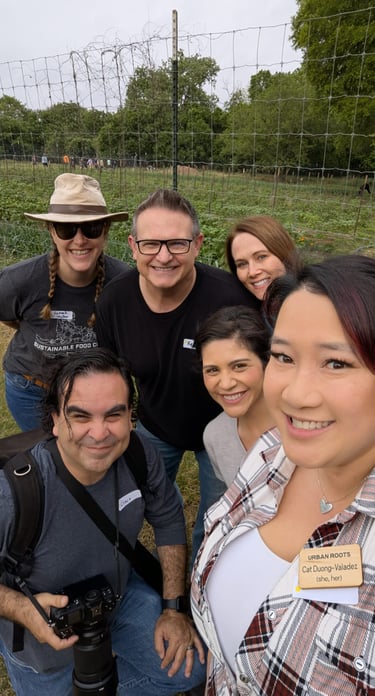 Francisco holds a camera, smiling with fellow volunteers in a joyful outdoor group selfie.