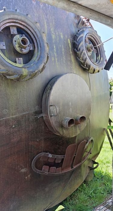 Creative face sculpture made from recycled metal parts and tractor tires on a rusty tank.