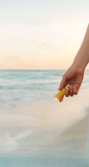 image of hand holding an essential oil bottle beachside
