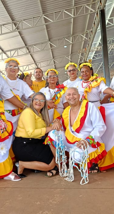 Seniors in colorful traditional folk costumes performing a cultural dance at an indoor community festival.