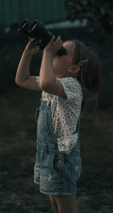 Fotografía de una niña mirando al cielo con prismáticos