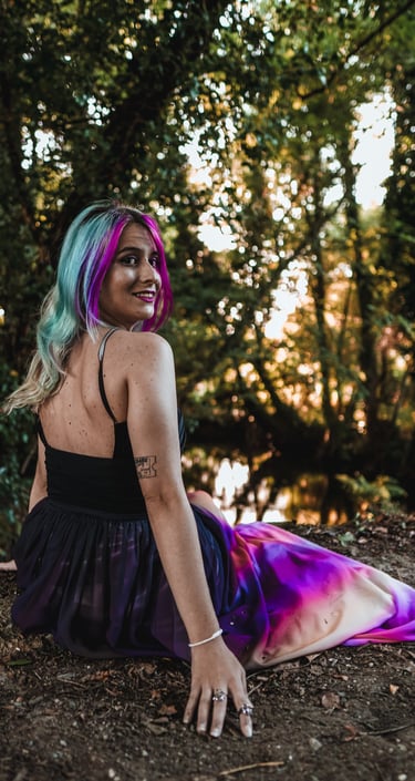 Fotografía de una mujer con vestido en el bosque, al lado del río