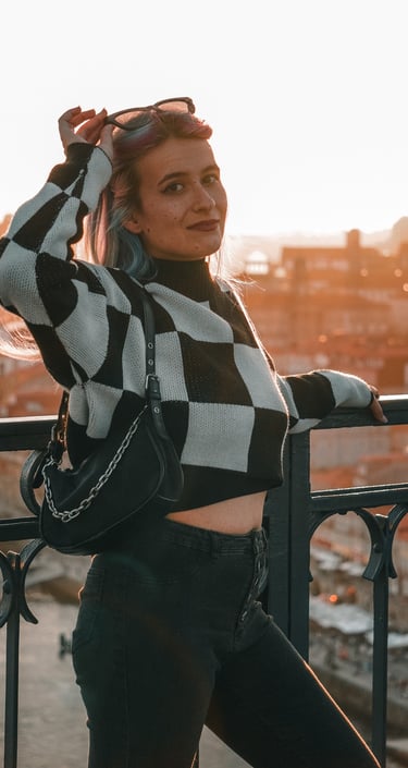 Fotografía de una mujer posando en el puente de Oporto, con la puesta de sol al fondo