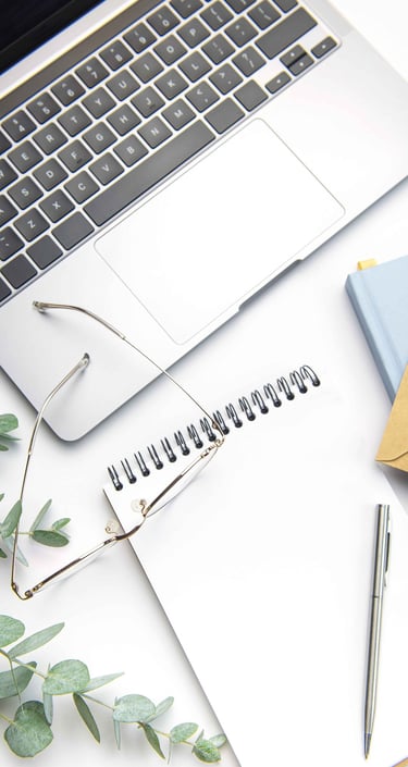Image of a notebook with a laptop, glasses and eucalyptus leaves