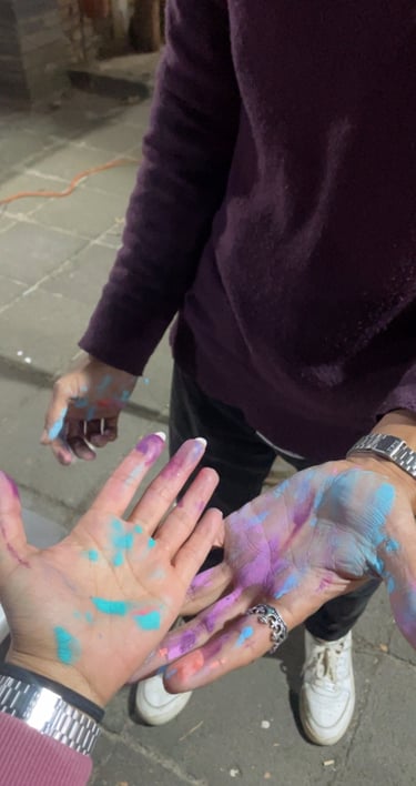 Manos cubiertas de pintura en polvo vibrante de color azul, morado y rosa 