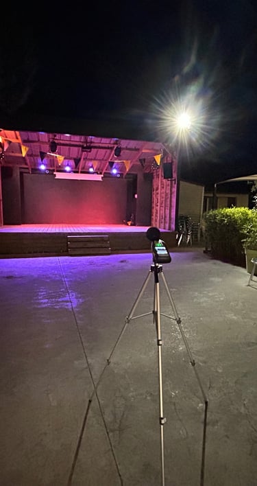 Scène extérieure la nuit avec éclairage violet et un sonometre sur un trépied