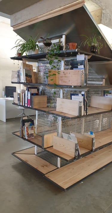 a wooden and steel library installed under a staircase in a mediatheque