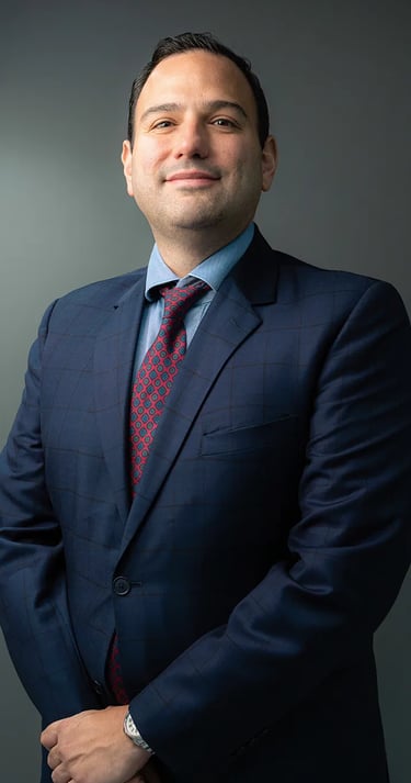 Fotografía profesional corporativo de hombre con terno azul, corbata roja en fondo gris de Quito, Ecuador