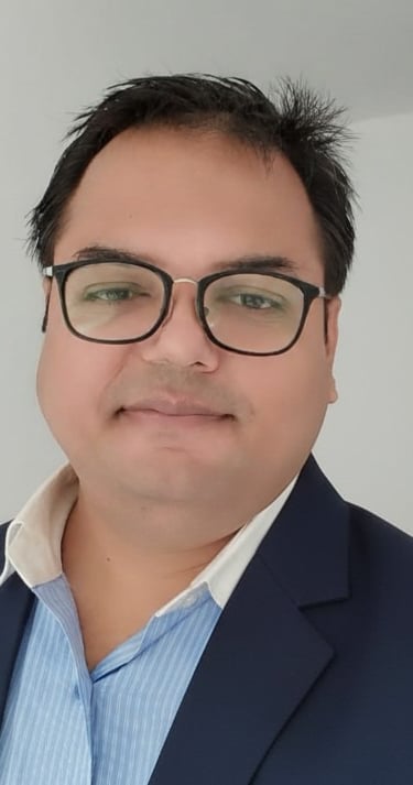 Professional headshot of a businessman wearing glasses and a navy blue blazer for a corporate profile.