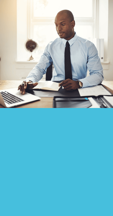 Homme en chemise bleue et cravate assis à un bureau