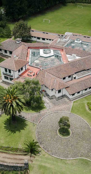 Fotografía con dron de mansión colonial de paredes blancas con techo naranja, cúpulas rodeada de naturaleza Quito Ecuador