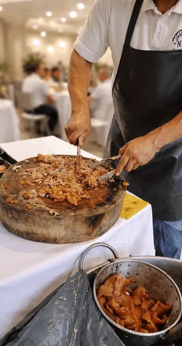 Taquero preparando carnitas en tabla de madera durante un evento, con invitados al fondo.