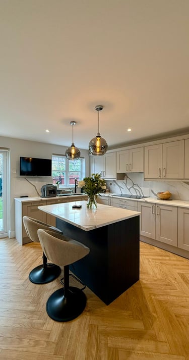 Modern shaker kitchen with grey cabinets, marble countertops, and a black island with bar stools.