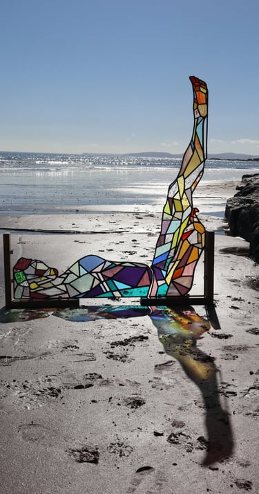 Full Sized Stained Glass Woman. Photograph is taken on a beach at low tide. Art work by Laura Kriefman