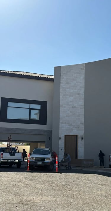 Casa moderna de dos pisos en construcción, con trabajadores y vehículos en el exterior