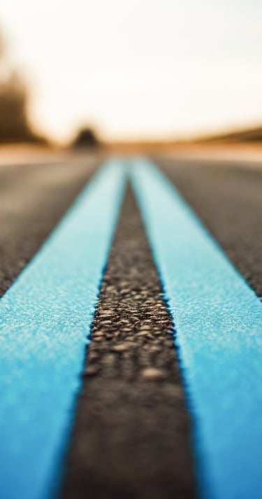 duas faixas contínuas de uma rodovia pintadas em azul claro que seguem em direção ao horizonte