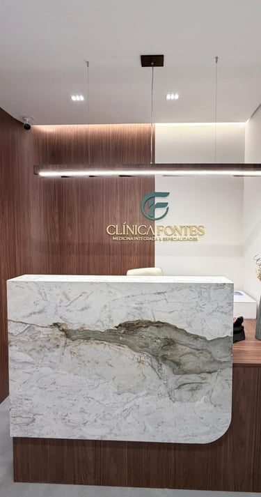 Recepção de clínica médica moderna com balcão em mármore, painéis de madeira e o logotipo da Clínica