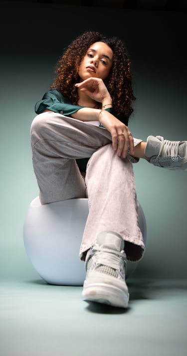 Young woman with curly hair wearing gray Nike Air Jordan sneakers and corduroy pants.