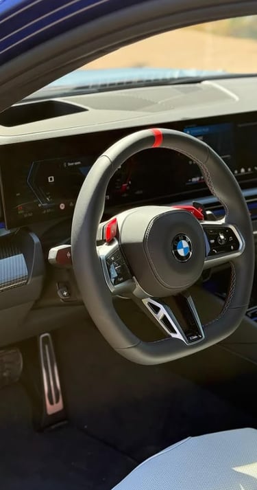 Interior view of a modern BMW M performance car featuring a digital dashboard and leather steering wheel.