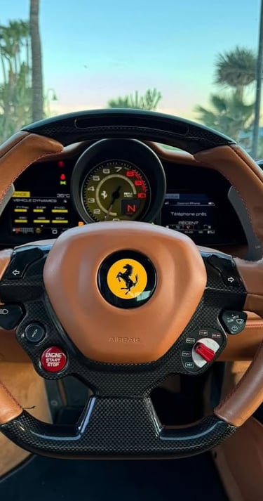Luxury Ferrari interior featuring a tan leather and carbon fiber steering wheel with the prancing horse logo.