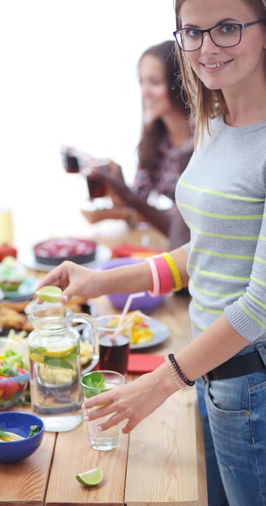 Vrouw die voor een tafel staat met een gezonde salade, symbool voor gezonde voeding of lifestyle.