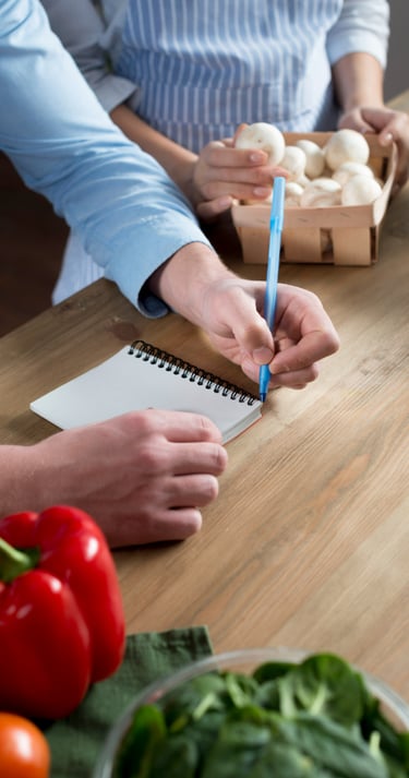 Man en vrouw werken samen aan een laptop en maken aantekeningen in een notitieboek.