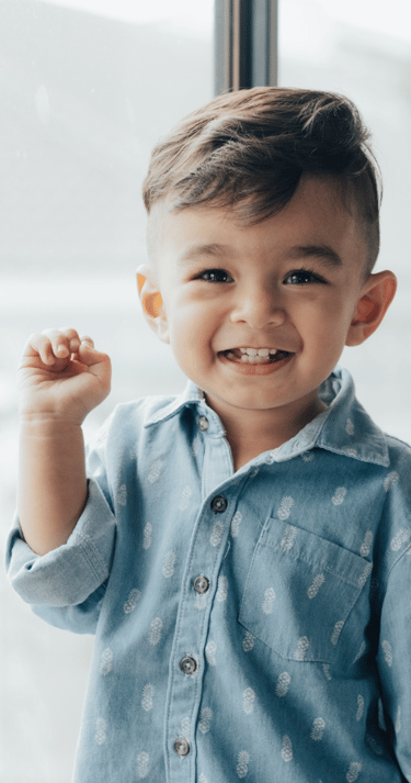 Smiling young boy in front of a window