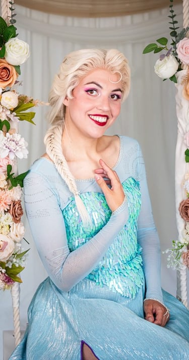 Een lachende ijskoningin in een lichtblauwe glitterjurk zit op een schommel versierd met bloemen.