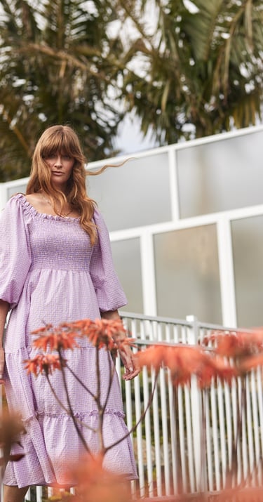 Fashion campaign photography - a woman in a purple dress standing in front of a fence