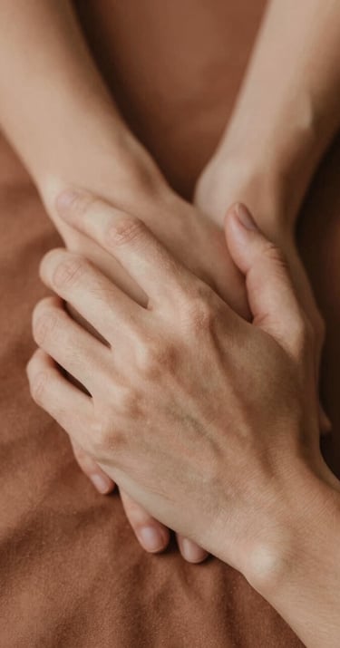 Close-up of hands intertwined, soft #AD7B5B terracotta fabric in the background, intimate and emotional storytelling photography.
