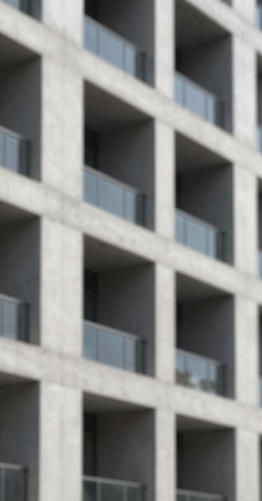 A close-up photograph of a modern concrete building facade featuring sharp shadows and a minimalist grid pattern, reflecting architectural rigor.
